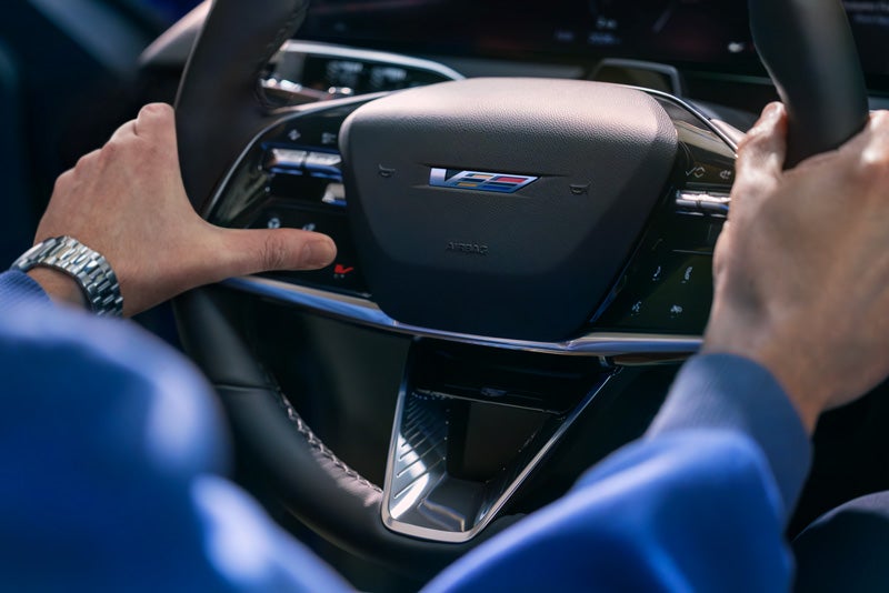 Close-up of a Man About to Press the V-Button on the 2026 OPTIQ-V Steering Wheel | Cadillac of South San Francisco in Colma CA