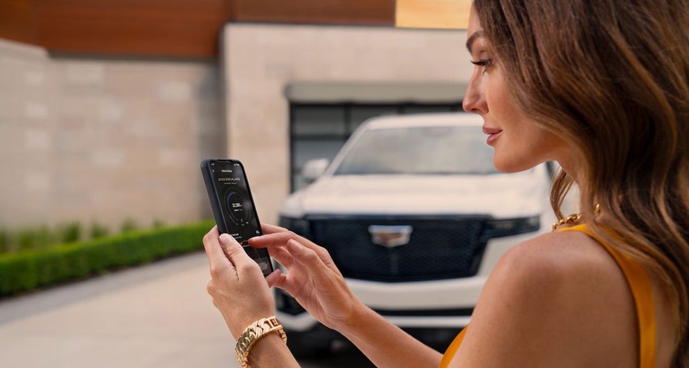 lady checking her mobile with a Cadillac vehicle background | Cadillac of South San Francisco in Colma CA